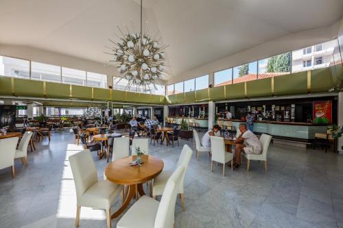 un restaurante con mesas y sillas y una lámpara de araña en Hotel Medena Budget en Trogir