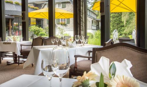 a restaurant with white tables and chairs and yellow umbrellas at Romantik Hotel Stryckhaus in Willingen