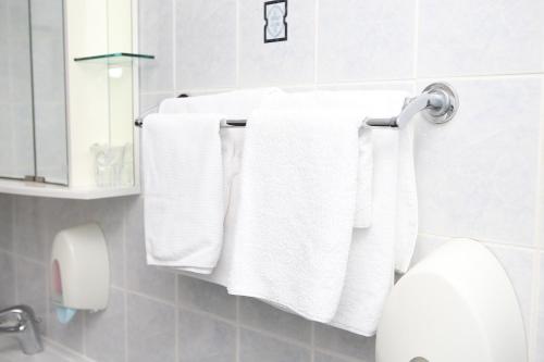 Un baño con toallas blancas colgando de un toallero. en Hotel Ana, en Gospić