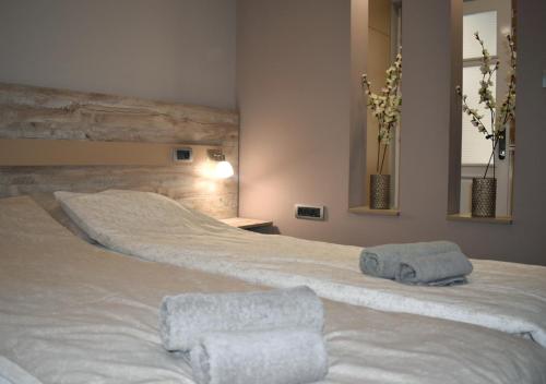 a bedroom with a large white bed with towels on it at Apartmani Zrenjanin in Zrenjanin