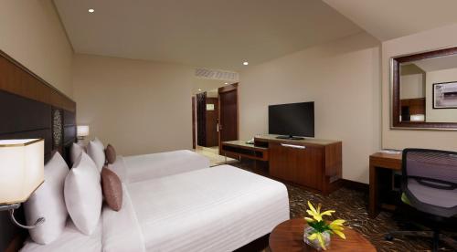 a hotel room with a bed and a television at Novotel Kochi Infopark in Cochin
