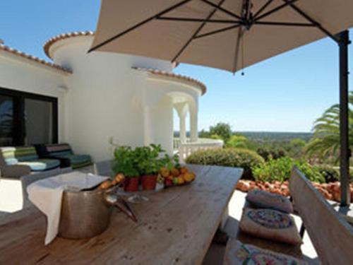 a wooden table with an umbrella on a patio at Luxurious Villa in Silves with Swimming Pool in Nora