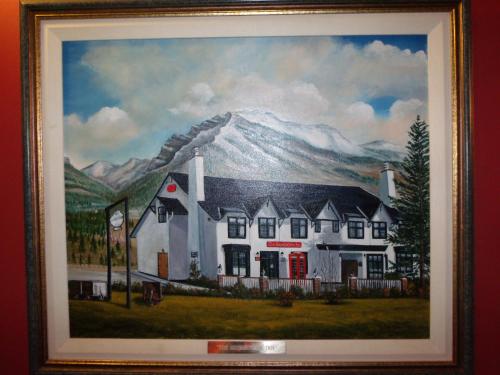 a painting of a house in front of a mountain at The Georgetown Inn in Canmore