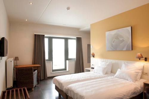 una camera da letto con un grande letto bianco e una finestra di B&B La Vie En Roses a Moorsel
