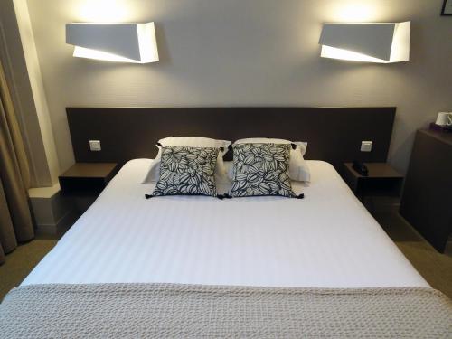a bedroom with a large white bed with pillows at Hotel Le Sevigne - Sure Hotel Collection by Best Western in Rennes