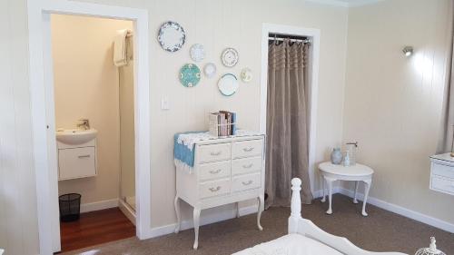 a white bedroom with a dresser and a table at Centennial House Taupo in Taupo
