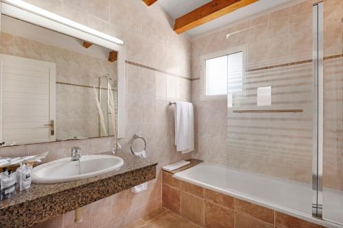 a bathroom with a tub and a sink and a mirror at TRH Tirant Playa in Fornells
