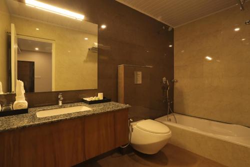 a bathroom with a toilet and a sink and a tub at D Fort Hotel Kollam in Kollam