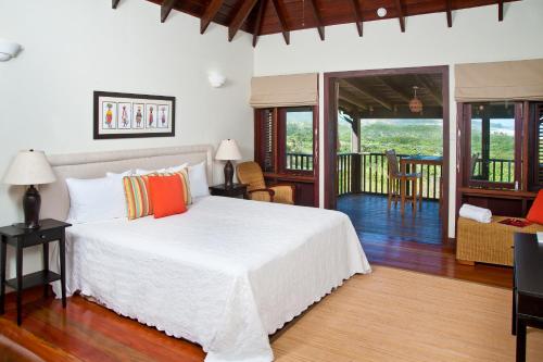 a bedroom with a white bed and a living room at Santosha Barbados in Saint Andrew