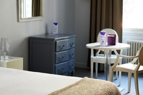 a bedroom with a blue dresser and a small table at Hotel Le Sevigne - Sure Hotel Collection by Best Western in Rennes