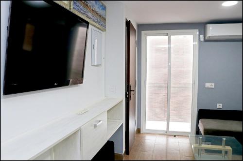 een woonkamer met een grote flatscreen-tv aan de muur bij Apartamento Baluarte in Conil de la Frontera