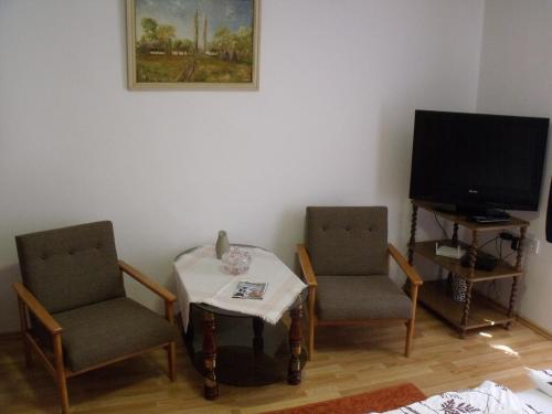 a living room with two chairs and a table and a television at Feszty-fészek Vendégház in Tiszafüred