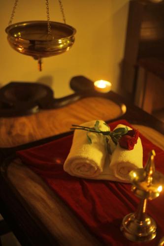 a table with two folded towels on a table with a candle at D Fort Hotel Kollam in Kollam