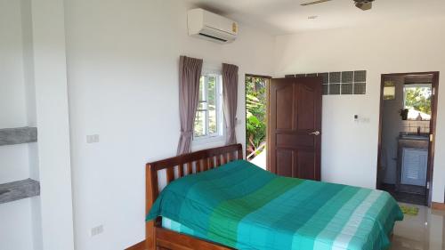 a bedroom with a bed with a blue and green blanket at Samui Grand Rock in Lamai