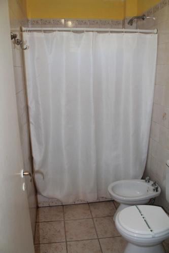 a bathroom with a white shower curtain and a toilet at Dennisse Hotel in Victoria