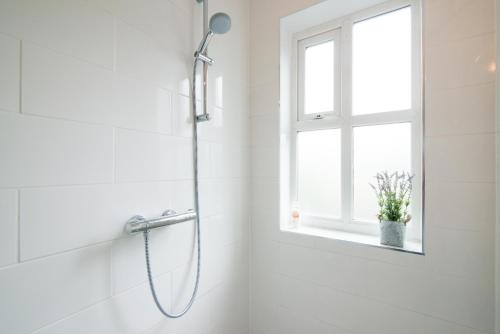 a shower in a white bathroom with a window at Burton House Boutique Flat in Manchester