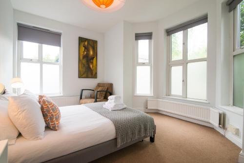 - une chambre avec un grand lit blanc et des fenêtres dans l'établissement Burton House Boutique Flat, à Manchester
