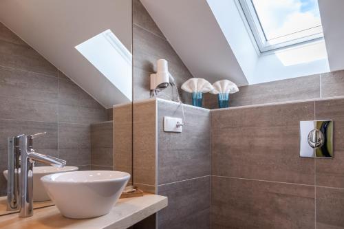 a bathroom with a sink and a skylight at Hostellerie Les Bagenelles in Sainte-Marie-aux-Mines