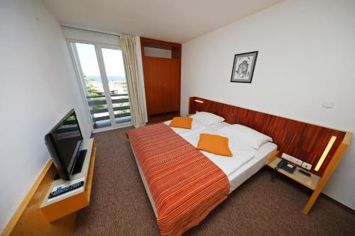 a bedroom with a bed and a flat screen tv at Hotel Donat - All Inclusive in Zadar