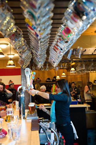 a woman is standing at a bar in a restaurant at The Alpenhof in Teton Village