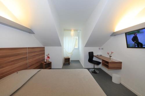 a bedroom with a bed and a tv on a wall at Logis Hôtel Restaurant L'Europe in Marvejols