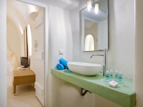 y baño con lavabo y espejo. en Christina's Cave House en Fira