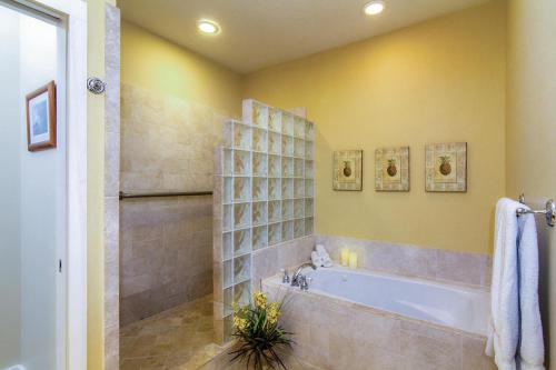a bathroom with a tub and a shower with yellow walls at Regency at Poipu Kai #914 in Koloa