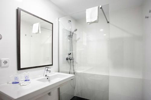 uma casa de banho branca com um lavatório e um chuveiro em Hotel Morlans em Paguera