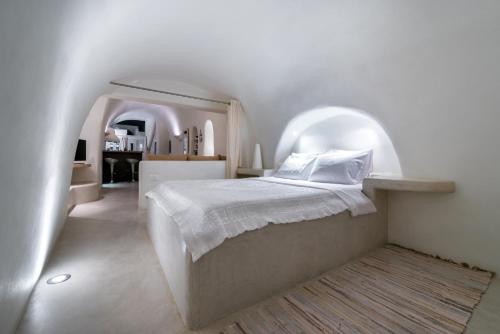 a white bedroom with a bed in an archway at Christina's Cave House in Fira