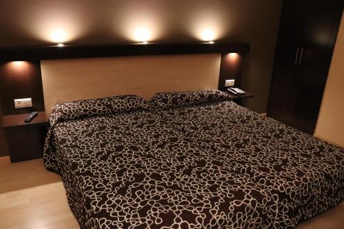 1 dormitorio con 1 cama con edredón blanco y negro en Hotel Acosta Ciudad de la Música, en Villafranca de los Barros