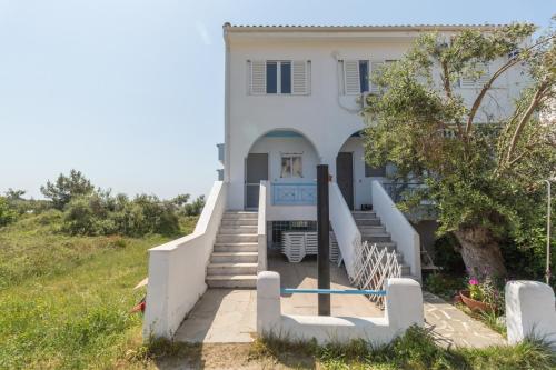 a white house with stairs in front of it at Alexger Gerakini Beach house view in Gerakini