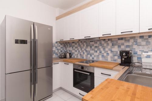 a kitchen with white cabinets and a stainless steel refrigerator at Alexger Gerakini Beach house view in Gerakini