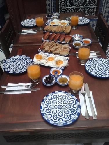 een houten tafel met borden met eten en sinaasappelsap bij Dar atlas in Fès