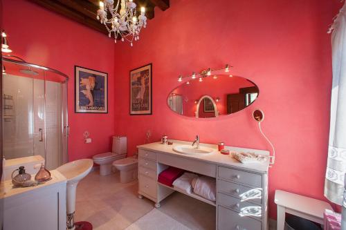 baño con paredes rojas, lavabo y espejo en Villa Irene en Casale sul Sile