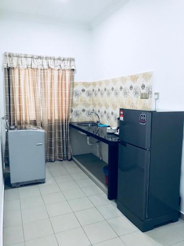 a kitchen with a counter and a sink and a refrigerator at Adina Drive-In Motel Cenang - Managed By Shell Out Resort in Pantai Cenang