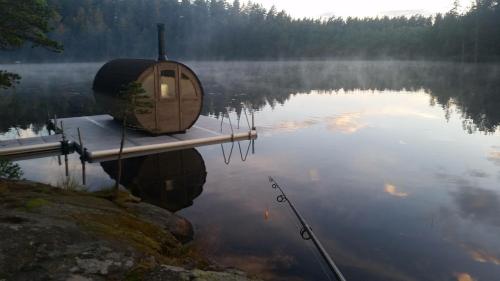 a small cabin on a dock on a lake at STF Kolarbyn Eco-Lodge in Skinnskatteberg