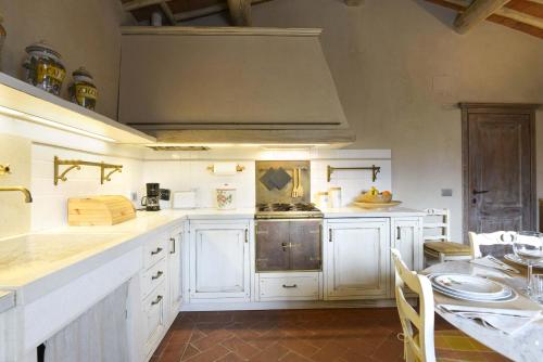 a large kitchen with white cabinets and a table at Casalta Di Pesa in Siena