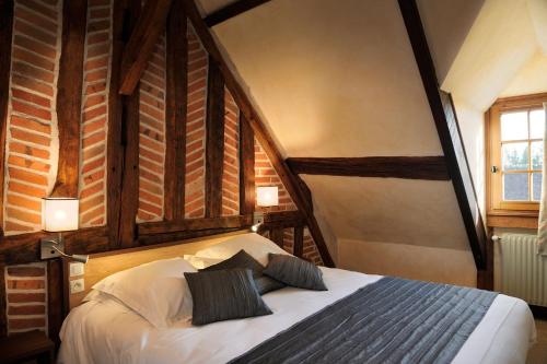 een slaapkamer met een bed met 2 kussens erop bij Logis Auberge À La Tête De Lard in La Ferté-Imbault