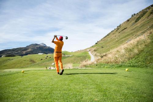 a man is playing golf on a green field at Andermatt Alpine Apartments in Andermatt
