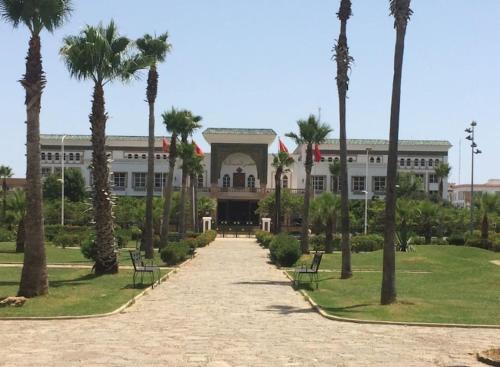 a large building with palm trees in front of it at Appartement De Luxe A Wilaya De Tetouan in Tetouan