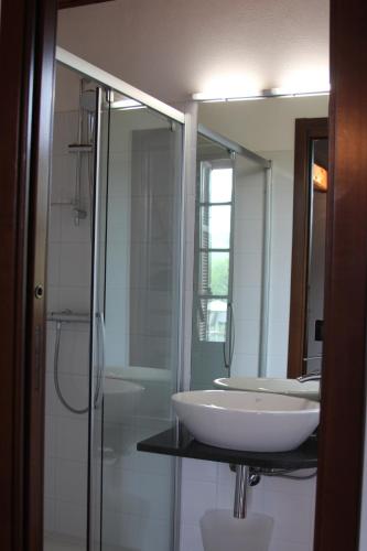 uma casa de banho com um lavatório, um chuveiro e um espelho. em Bed and Breakfast Cascina Beccaris em Costigliole dʼAsti