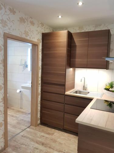 a kitchen with wooden cabinets and a sink at Hotel Garni Gasthof Bucksande in Apen