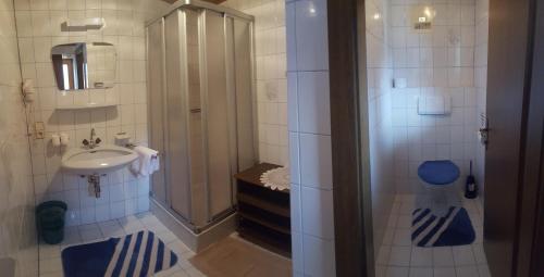 La salle de bains est pourvue d'un lavabo et d'une douche avec des tapis bleus. dans l'établissement Gästehaus Eberl - Rita, à Finkenberg