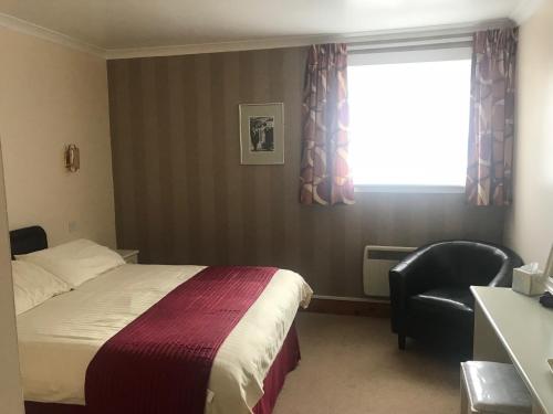 a bedroom with a bed and a chair and a window at Empire Travel Lodge in Lochgilphead