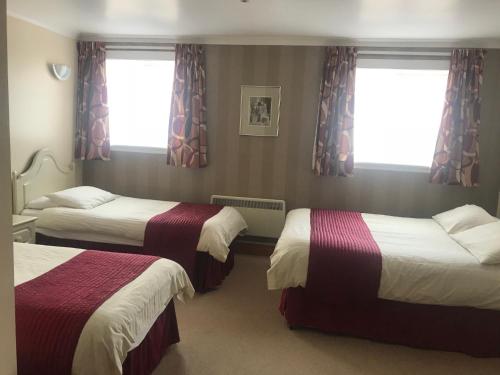 a hotel room with two beds and two windows at Empire Travel Lodge in Lochgilphead