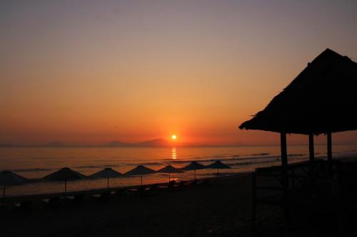a sunset on the beach with umbrellas and the ocean at Santa Sea Villa in Hoi An