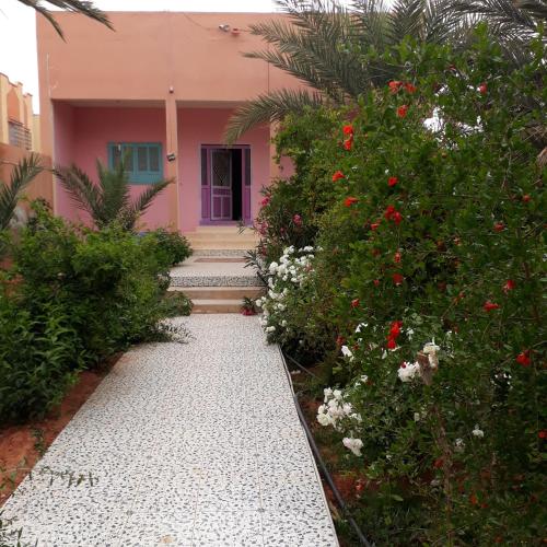 a pink house with flowers in front of it at Oasispalmares in Er Rachidia