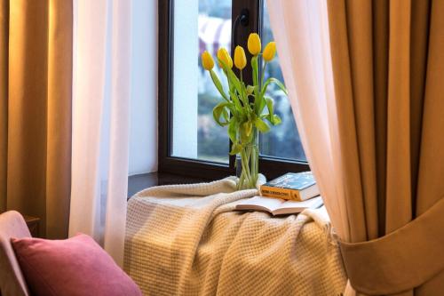 a table with a vase with yellow flowers in a window at Park Hotel Warshawskiy in Sarny