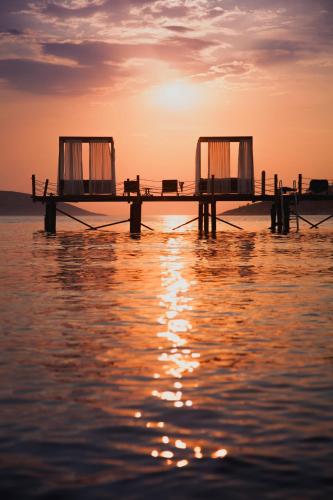 a dock on the water with the sunset in the background at Sirene Luxury Hotel Bodrum in Yalıkavak
