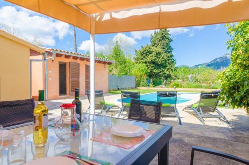 a patio with a table with wine glasses and an umbrella at S'Alqueria in Campanet